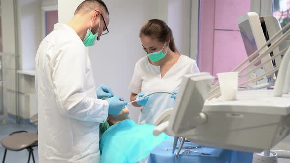 Dentist and his assistant examining the teeth of a patient