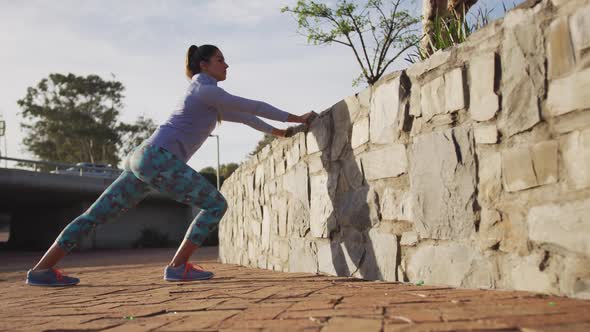 Caucasian woman stretching against a wall