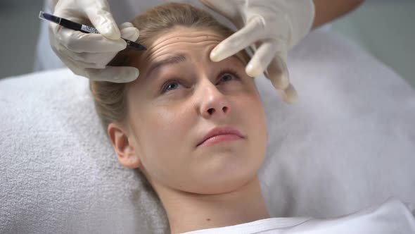 Experienced Cosmetologist Marking Position of Wrinkles on Girls Forehead