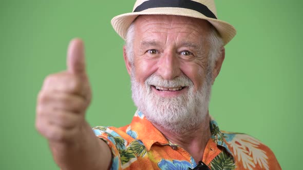 Handsome Senior Bearded Tourist Man Ready for Vacation Against Green Background