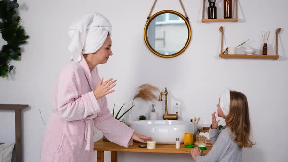 Little Girl with Mother Applying Creme To Skin