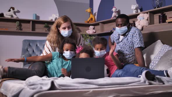 Family in Face Masks During Video Chat on Laptop