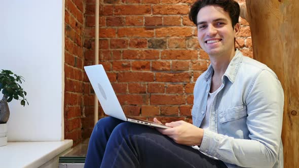 Portrait of Smiling Young Man Sitting on Relaxing Chair