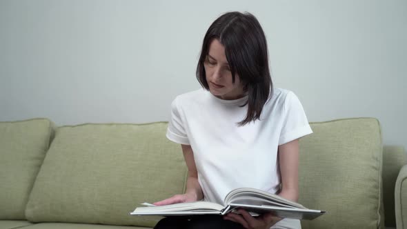 Brunette Woman Reading Sitting Lying on the Sofa