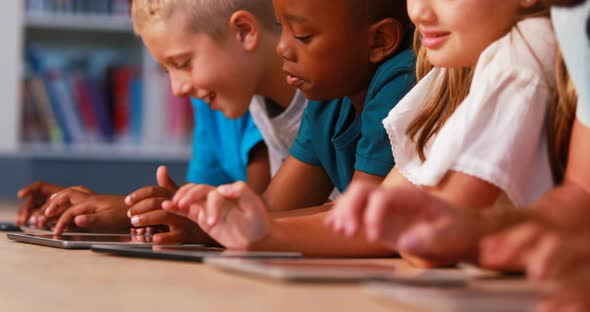 School kids using digital tablet in library alt