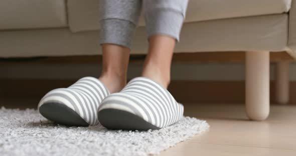 Woman wear fleece slippers and sit on sofa