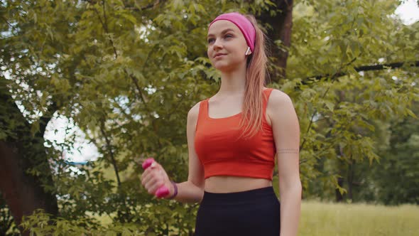 Athletic Young Sporty Fit Girl Doing Dumbbells Workout in Sunny Park Performing Bicep Exercising