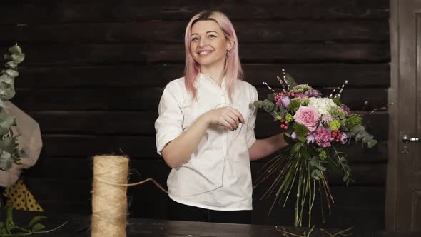 A Young Smiling Woman in White Playfully Unwinds the Twine Cuts Off a Piece and Tightens Stems of