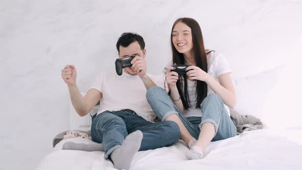 Pretty Girl and Boyfriend Are Playing Play Station in Bed