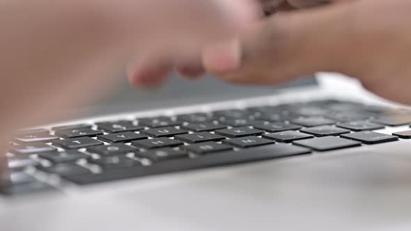 Rear View of Fingers of African Man Typing on Laptop Keyboard 