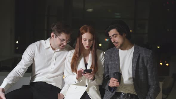 Work Colleagues In Strictly Business Clothes Talk Drink Coffee During A Break Late At Night in the