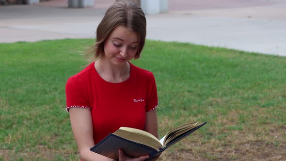 A student muses at the passage in a book while studying in the campus commons.