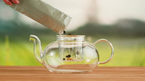 Putting Dry Tea Leaves Into Teapot on a Wooden Table