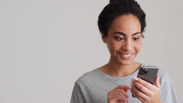 Smiling African woman in t-shirt leafing tape by phone