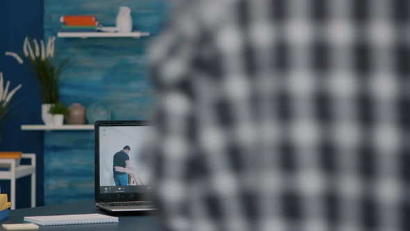 Happy Senior Man Waving During Video Conference with Nephews Using Laptop