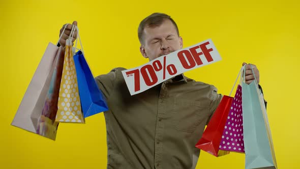 Surprised Man Showing Shopping Bags and Up To 70 Percent Off Inscription in His Mouth. Black Friday