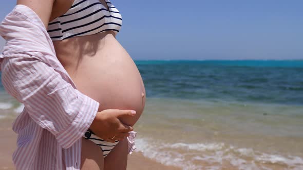 Pregnant Woman In Bikini Touching Her Belly At The Beach. 