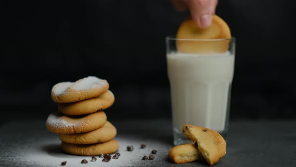 Homemade cookies with chocolate and icing sugar with milk on a black background