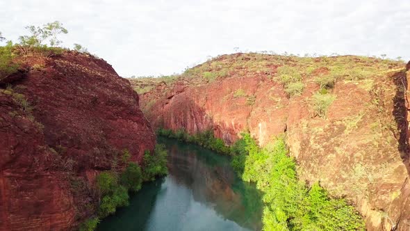 Drone flying through straight through a gorge/canyon with large red rock walls on either side and a