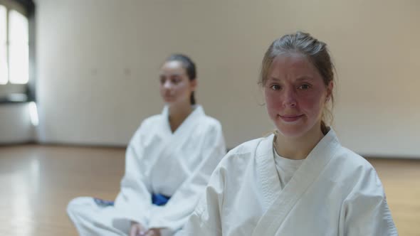 Front View of Cheerful Martial Artsist Sitting on Floor in Gym