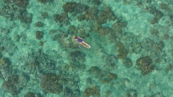 Aerial: woman snorkeling on coral reef tropical caribbean sea turquoise water