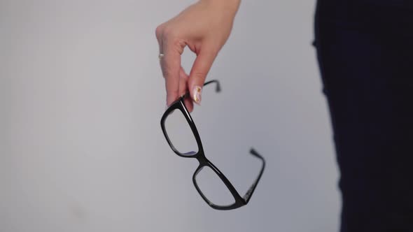 Female Hand is Holding Model of Eyeglasses with Black Rim