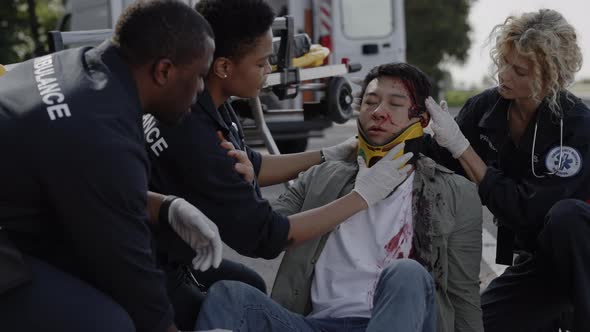 Multiracial Group of Paramedics Helping Asian Man on Road