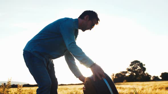 Musician opens guitar case during golden hour in field