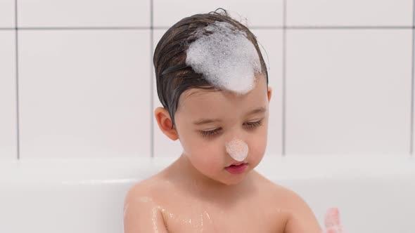 Three Year Old Child with Big Brown Eyes Is Sitting in a White Bathroom