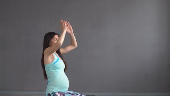 Girl Practicing Yoga. Pregnant Woman Doing Breathing Exercises While Sitting on the Knees.