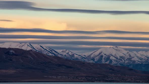 Full Moon setting at sunrise as it moves behind colorful clouds