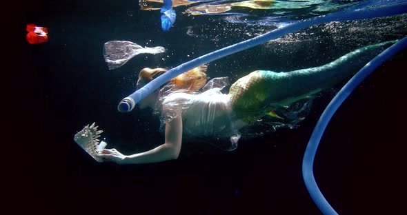 Mermaid Is Floating Underwater of Ocean, Looking on Plastic Waste