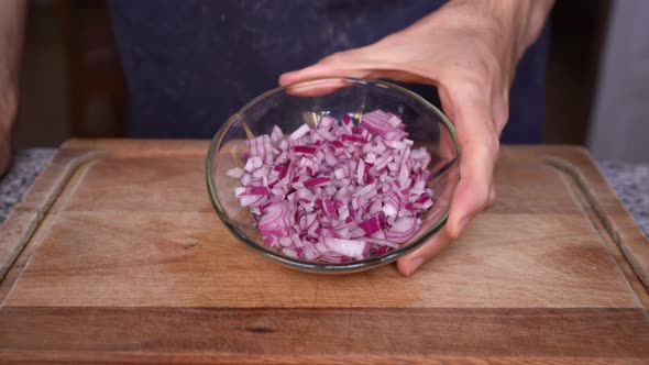 Cook showing purple onion cut in dices (brunoise cut)