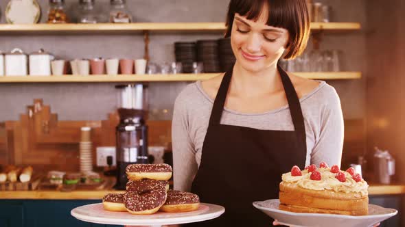 Portrait of waitress holding doughnuts and cake in caf������������