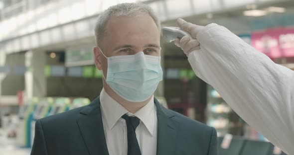 Close-up Portrait of Mid-adult Businessman in Face Mask Standing in Airport Departure Area As