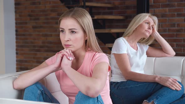 Frustrated Young Adult Woman and Mature Mother Turn Back on Sofa After Conflict