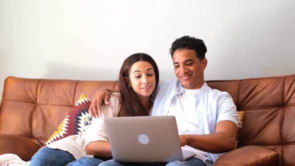 Young boy and girl together at home enjoying laptop computer sitting on the floor smiling
