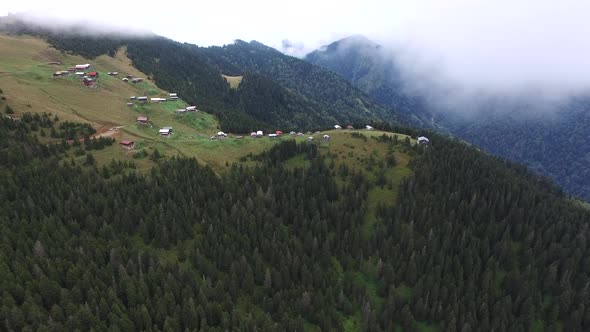 Forested Mountain Plateau Houses Through the Clouds in Grassland