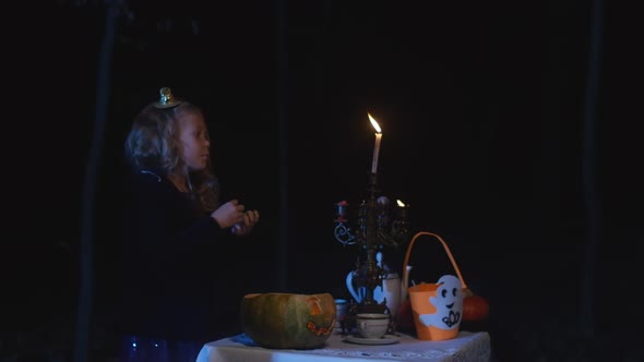 Side View Cute Little Girl Standing in Darkness in Forest with Halloween Jackolantern and Candles