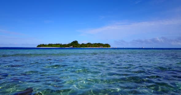 Beautiful flying clean view of a white paradise beach and aqua blue water background in colorful 