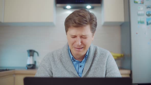 Young Attractive Man Crying While Sitting at Laptop