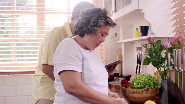 Asian elderly couple cut tomatoes prepare ingredient for making food in the kitchen.