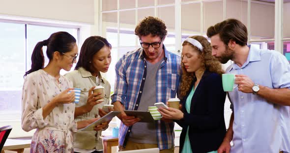 Group of business executives having coffee while interacting over digital tablet