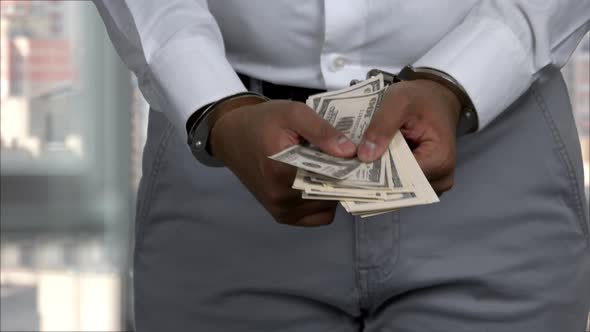 Brownskined Man in Handcuffs Holds Money Closeup