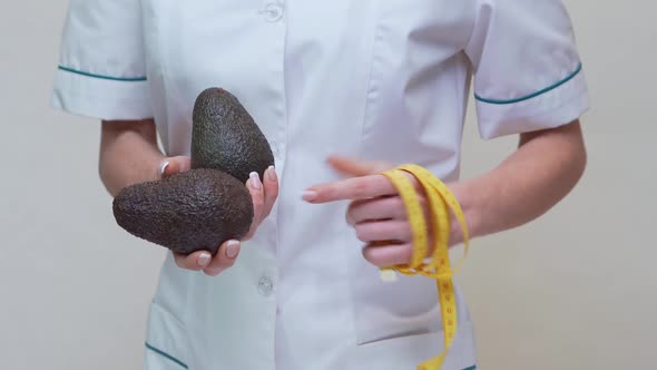 Nutritionist Doctor Healthy Lifestyle Concept - Holding Organic Avocado Fruit and Measuring Tape