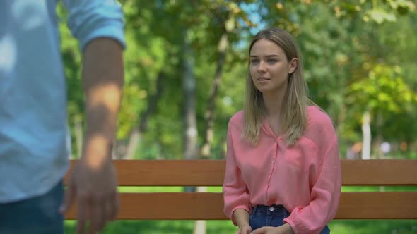 Man Leaving Upset Girlfriend Alone on Bench in Park, Walking Away, Break-Up