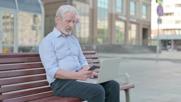 Old Man Using Smartphone and Laptop While Sitting Outdoor on Bench