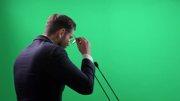 Back View of an Elegant Man in Suit Standing on a Green Background the Lecturer Speaks to the