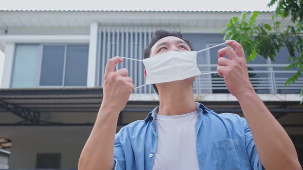 Portrait of Asian man removing protective face mask then take deep breath after quarantine.