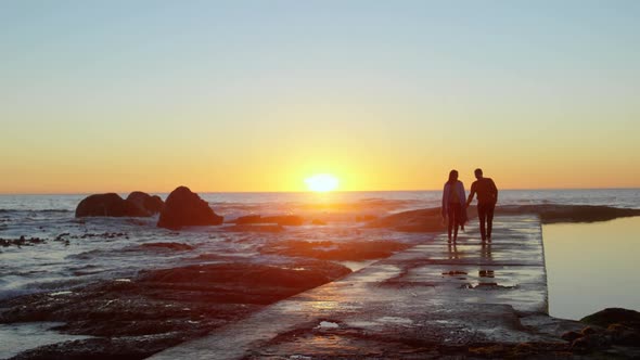 Couple walking hand in hand on the pier during sunset 4k